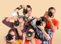 Group of professional photographers with cameras on beige background Royalty Free Stock Photo