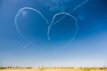A group of professional pilots of aircraft of fighters on a sunny clear day shows tricks in the blue sky, drawing a romantic heart Royalty Free Stock Photo