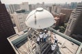 a group of professionals installing a satellite dish on the roof of a tall building Royalty Free Stock Photo