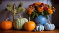 a group of pumpkins sitting on top of a table next to a vase filled with flowers and a blue vase filled with orange flowers Royalty Free Stock Photo