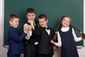 Group pupil as a gang, posing near blank chalkboard background, grimacing and emotions, dressed in classic black suit