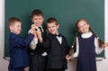 Group pupil as a gang, posing near blank chalkboard background, grimacing and emotions, dressed in classic black suit