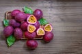 A group of purple skin passionfruit plant, sliced and round fruits in a wooden tray on wood table, top view image