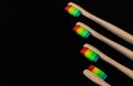 Group of rainbow eco bamboo toothbrushes, on black background. Royalty Free Stock Photo