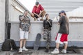 Group of rappers posing against the wall on the metal rooftops