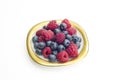 Group of raspberries and bilberries placed on a golden dish wit