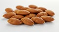 A group of raw almonds (Prunus dulcis) is scattered across a smooth, light surface. Royalty Free Stock Photo