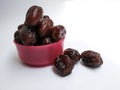 Group of Raw Dry Dates Brown Color Fruit in a Plastic Pink Bowl on white Background