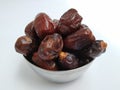 Group of Raw dry Dates Brown Color Fruit in a steel bowl isolated on white Background