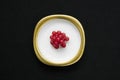 Group of red currants placed on a golden dish with isolated black background Royalty Free Stock Photo