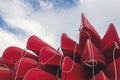 group of red kayaks piled up against each other on the shore seen from below Royalty Free Stock Photo