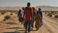 group of refugees walk along a dusty desert road in search of a better life
