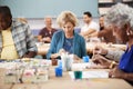 Group Of Retired Seniors Attending Art Class In Community Centre With Teacher