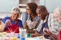 Group Of Retired Seniors Attending Art Class In Community Centre With Teacher