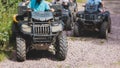 Group of riders riding ATV vehicle crossing forest rural road, process of driving rental vehicle, all terrain quad bike vehicle, Royalty Free Stock Photo