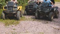 Group of riders riding ATV vehicle crossing forest rural road, process of driving rental vehicle, all terrain quad bike vehicle, Royalty Free Stock Photo