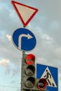 A group of road signs and a traffic light with an additional section at the intersection against the sky. A red traffic light and Royalty Free Stock Photo