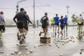 Group of runners on marathon near point of refreshment. Pile of used disposable cardboard cups for water on asphalt