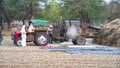 Group of rural farmers separating Barley or Rye from stalk using a Tractor operated thresher machine