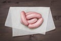 A Group Of Sausages In The Butcher Shop On The White Parchment Paper. Frankfurter Ready For Sale. Everyday Food For Bbq.
