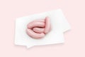 A group of sausages on the white parchment paper. Frankfurters isolated on pink background.