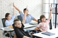 Group of school kids raising hands in classroom education concept Royalty Free Stock Photo