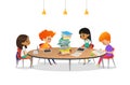 Group of school children sitting around circular table with large pile of books on it, reading and preparing for lesson Royalty Free Stock Photo