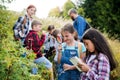 Group of school children with teacher on field trip in nature, learning science.