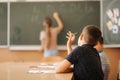 Group of school kids with pens and notebooks writing test in classroom. education, elementary school, learning and Royalty Free Stock Photo