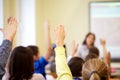 Group of school kids raising hands in classroom