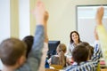 Group of school kids raising hands in classroom