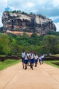 Group of school students walking in garden complex with rock of Sigiriya as backdrop