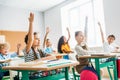 group of schoolchildren raising hands to answer question