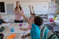 Group of schoolchildren raising their hands in an elementary school classroom