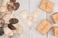 group of sea shells, pearls laid out in the shape of heart and gift boxes on white wooden background Royalty Free Stock Photo