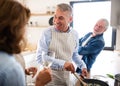 Group of senior friends at dinner party at home, cooking. Royalty Free Stock Photo