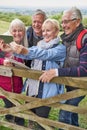 Group Of Senior Friends Hiking In Countryside Standing By Gate  And Taking Selfie On Mobile Phone Royalty Free Stock Photo