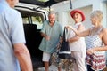 Group Of Senior Friends Loading Luggage Into Trunk Of Car About To Leave For Vacation