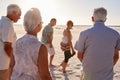 Group Of Senior Friends Walking Along Sandy Beach On Summer Group Vacation Royalty Free Stock Photo