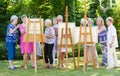 Group of senior ladies enjoying an art class outdoors in a park or garden as a therapeutic recreational activity at a care home.