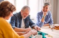 Group of senior people playing board games in community center club.