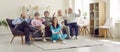 Group of senior people watching TV in retirement home together with young nurse. Royalty Free Stock Photo