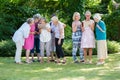 Group of senior women gladly looking at pictures and discussing them, standing in the park after art therapy lesson.