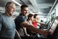 A group of seniors in gym with a young trainer doing cardio work out.