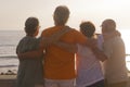 Group of seniors hugged together at the beach looking at the sea with a beautiful sunset - family enjoying at vacation Royalty Free Stock Photo