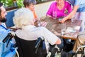 Group of seniors and nurse playing cards in rest home