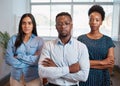 Group of serious business people pose arms folded in office, diverse trio