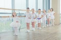 Group of seven little ballerinas standing in row and practicing ballet using stick on the wall Royalty Free Stock Photo