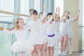 Group of seven little ballerinas standing in row and practicing ballet using stick on the wall Royalty Free Stock Photo