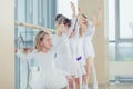 Group of seven little ballerinas standing in row and practicing ballet using stick on the wall Royalty Free Stock Photo